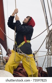 Young Sailor On A Ship's Deck Hoisting A Sail