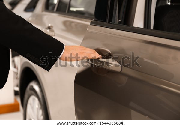 Young
salesman in suit opening car door, closeup
view