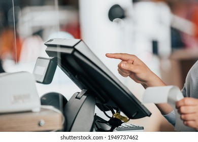 Young saleswoman doing process payment on the touchscreen POS, counting sale in the cash register, finance concept