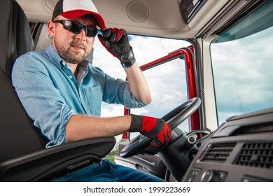 Young And Satisfied Caucasian Semi Truck Driver In His 30s Inside Truck Tractor Cabin. Transportation Theme.