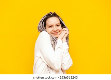 young satisfied girl with colored dreadlocks is touched and thanks on a yellow isolated background, a modest woman with a unique hairstyle is shy and smiles - Powered by Shutterstock