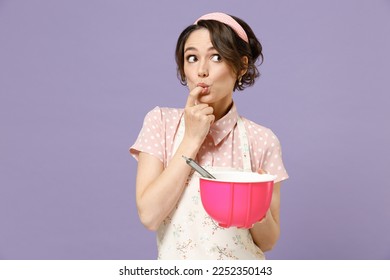 Young satisfied happy fun housewife housekeeper chef cook baker woman wearing pink apron beating egg yolks whites lick finger taste isolated on pastel violet background. Cooking food process concept. - Powered by Shutterstock