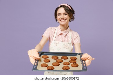 Young Satisfied Happy Housewife Housekeeper Chef Cook Baker Woman In Pink Apron Showing Chocolate Cookies Biscuits On Baking Sheet Isolated On Pastel Violet Background Studio. Cooking Food Concept.