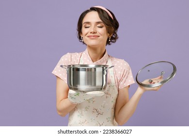 Young satisfied happy housewife housekeeper chef cook baker woman in pink apron holding soup stainless pan saucepan sniff smell isolated on pastel violet background studio Cooking food process concept - Powered by Shutterstock