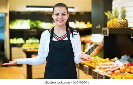 Young satisfied  shopping assistant demonstrating assortment of grocery shop