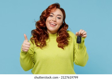 Young satisfied smiling happy chubby overweight plus size big fat fit woman wear green sweater hold car keys fob keyless system show thumb up isolated on plain blue background People lifestyle concept