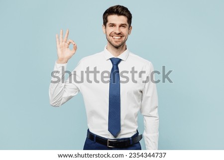 Young satisfied successful employee business man corporate lawyer wear classic formal shirt tie work in office showing okay ok gesture isolated on plain pastel light blue background studio portrait