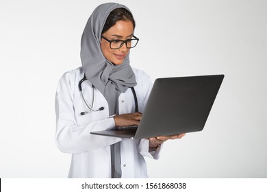 Young Saudi female doctor wearing doctor uniform and Hijab and Stethoscope in various positions, expresseions and hand gestures on white isolated background.
