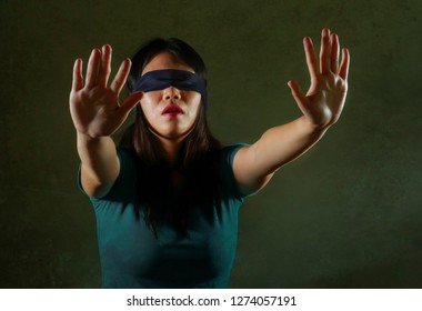 Young Scared And Blindfolded Asian Chinese Teenager Girl Lost And Confused Playing Dangerous Internet Viral Challenge Isolated On Dark Background Under Edgy And Dramatic Studio Light