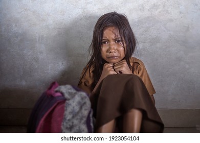 young scared and helpless 7 or 8 years old female child in school uniform suffering discrimination and harassment at school sitting on floor crying in bullying problem concept