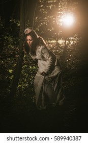 Young Scared Lonely Woman Walking Through The Forest At Night In White Dress. 