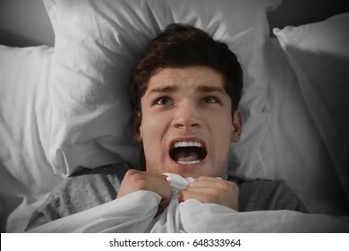 Young Scared Man Lying In Bed At Home