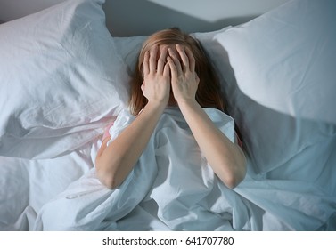 Young Scared Woman Lying In Bed At Home