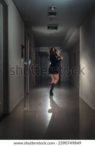 A young scared woman in a panic runs away along a dark corridor. Negative emotions.