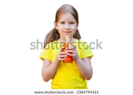 Young school age child girl holding a glass bottle full of juice in hands in front of her, one person isolated on white background, cut out, front view, frontal shot. Healthy food products, beverages
