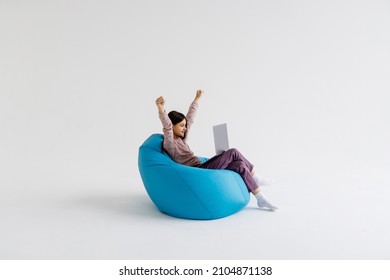 Young School Girl Dressed Casual Clothes Rising Fists Looking Modern Laptop Sitting Bean Bag On White Background