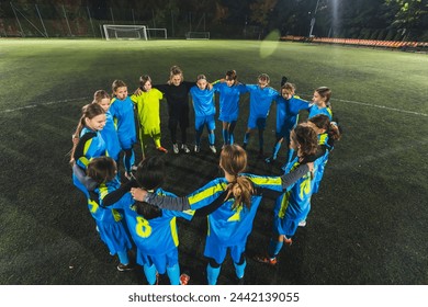 young school girls and their female coach standing in a circle and huddling before starting practice, soccer and teamwork. High quality photo - Powered by Shutterstock