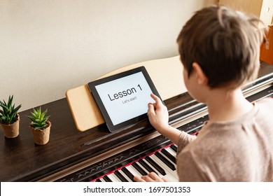 Young schoolboy playing classic digital piano at home during online class at home, social distance during quarantine, self-isolation, online education concept