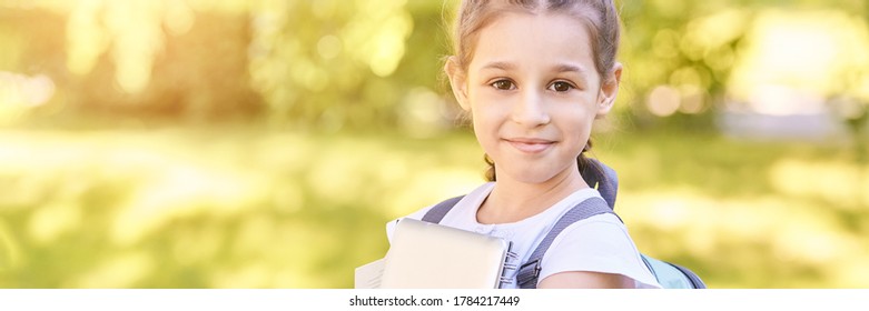 Young schoolgirl with backpack. Lifestyle going to classroom. Outdoor autumn park. Children learn smart. Street student. Happy preschool kid. Back to school