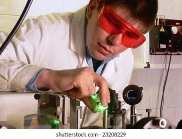 The young scientist does experiences with a green beam of the laser in laboratory.