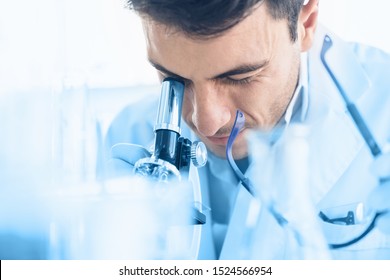 Young scientist look through microscope while doing research in scientific laboratory. Health and Medical specialist doctor working in lab
