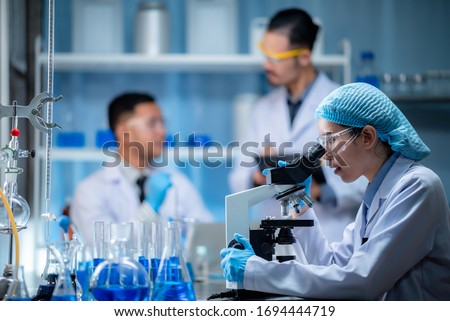 Young scientist looking through a microscope in a laboratory. Young scientist doing some research, study for making vaccine to protection a coronavirus COVID-19