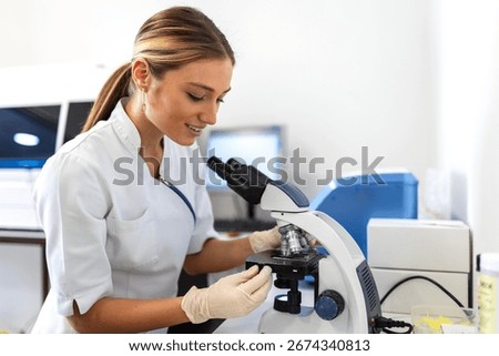 Young scientist looking through a microscope in a laboratory. Young scientist doing some research.