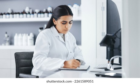 Young scientist using a computer and microscope in a lab. Female pathologist analyzing medical samples while doing experiments to develop a cure. Microbiologist conducting forensic research