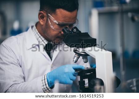 Young scientist working with a microscope in a laboratory. Young scientist doing some research.