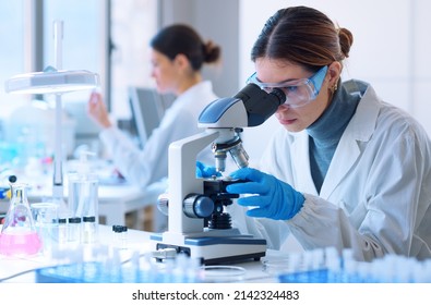 Young scientists conducting research investigations in a medical laboratory, a researcher in the foreground is using a microscope - Powered by Shutterstock