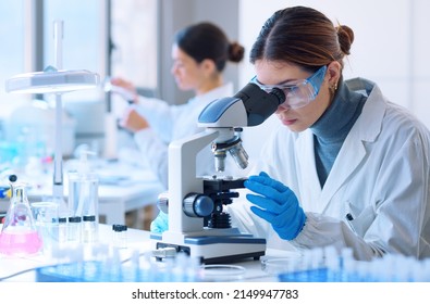 Jóvenes científicos que realizan investigaciones en un laboratorio médico, un investigador en primer plano está utilizando un microscopio