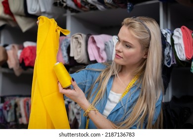 A young seamstress selects threads for the chosen yellow fabric. - Shutterstock ID 2187136783