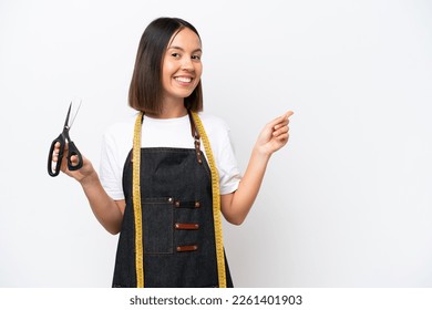 Young seamstress woman isolated on white background pointing finger to the side