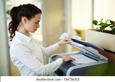 Young secretary making photocopies on xerox machine in office