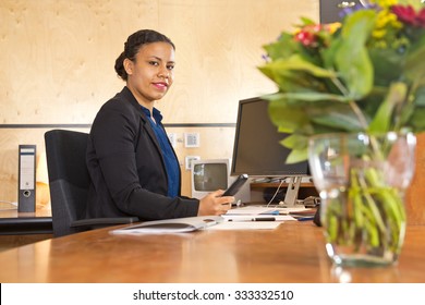 Young Security Guard Manning The Front Desk Of A Large Company During The Night Shift, With A Computer Monitor And Cctv Monitor, Holding A Phone.