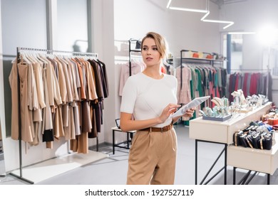 Young seller using digital tablet while standing in showroom with clothes  - Powered by Shutterstock