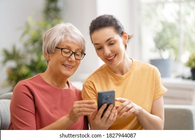 Young and senior women are using smartphone. Daughter is helping mother having fun staying at home. - Powered by Shutterstock