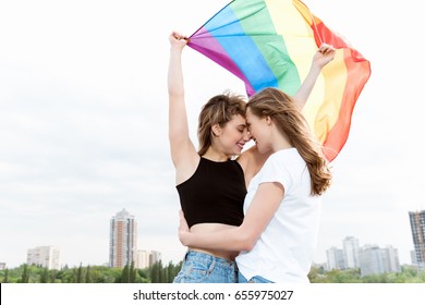 Young Sensual Lesbian Couple Embracing And Waving Lgbt Flag Outdoors