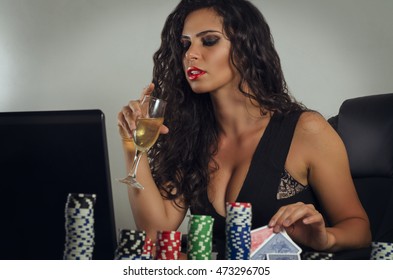 Young sensual woman drinking champagne and playing poker online, selective focus on face