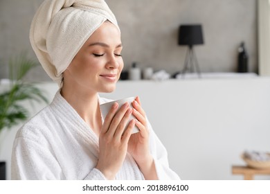 Young Serene Relaxed Woman In Spa Bath Towel Drinking Hot Beverage Tea Coffee After Taking Shower Bath At Home. Beauty Treatment, Hydration Concept