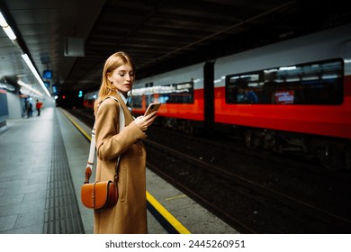 Young serious businesswoman in suit surfing wireless internet on smartphone in metro - Powered by Shutterstock