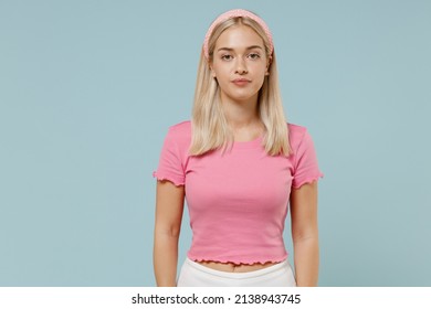Young serious calm beautiful caucasian blonde woman 20s wearing casual pink t-shirt headband looking camera isolated on plain pastel light blue background studio portrait. People lifestyle concept.