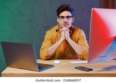 Young Serious Calm Employee Programmer IT Specialist Business Man In Casual Shirt Sit Work At Office Desk With Pc Laptop Desktop Computer Prop Up Chin Achievement Career Program Development Concept