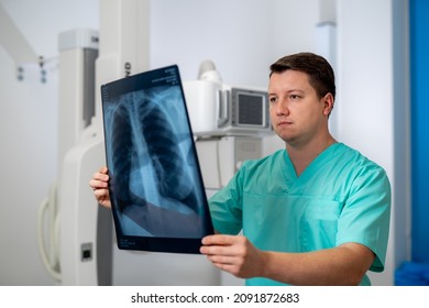 Young serious competent male doctor looking at X-ray at doctor's office. Computer tomography background. Stock photo - Powered by Shutterstock