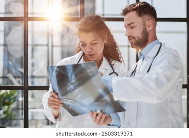 Young serious competent male doctor looking at X-ray at doctor's office - Powered by Shutterstock