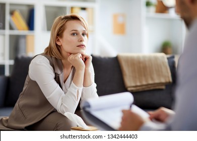 Young Serious And Concentrted Woman Listening To Her Counselor While Sitting On Couch During Consultation