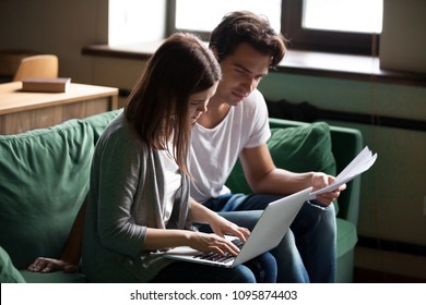 Young serious couple calculating domestic bills online, managing finances or taxes with laptop application and papers, millennial clients customers reviewing bank accounts, planning budget expenses