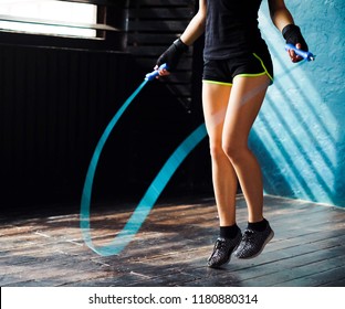 young serious female boxer in wrapped hands warming up, jumping on skipping rope in gym. Fit woman preparing to boxing competition. Wellness, fighting, motivation, self defense concept - Powered by Shutterstock