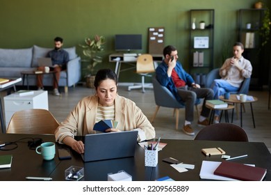 Young Serious Female Designer With Color Palette Looking At Laptop Screen While Watching Online Video About Creating New Products