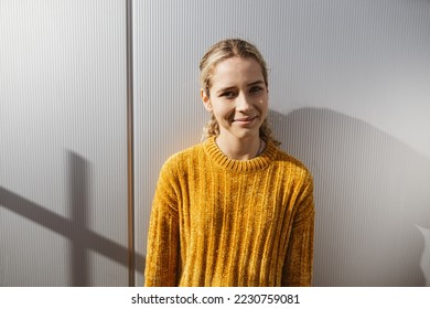 Young serious girl stands in front of metal wall and looks at camera with smile